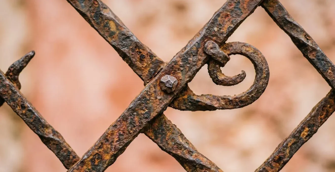 Extreme close-up of intricate iron window grill patterns showing craftsmanship details and rust patina.