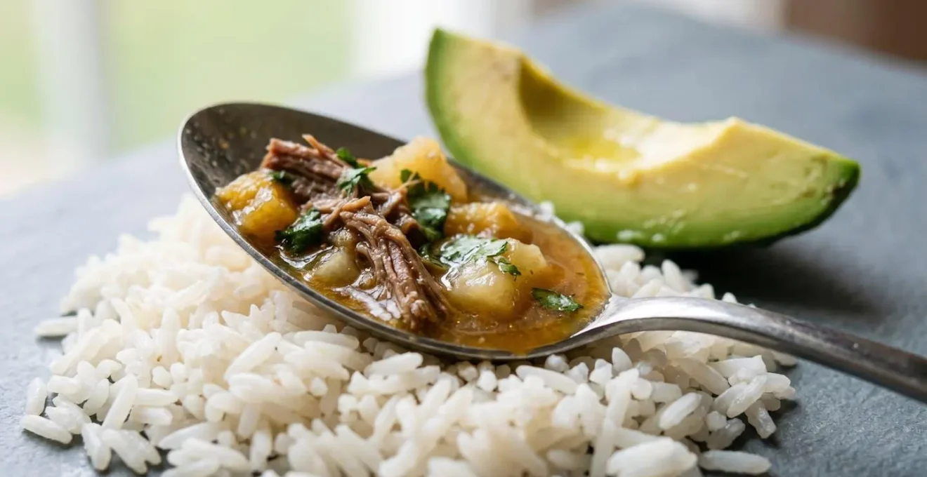 Close-up of white rice, creamy avocado slices, and sancocho stew showing the traditional serving combination